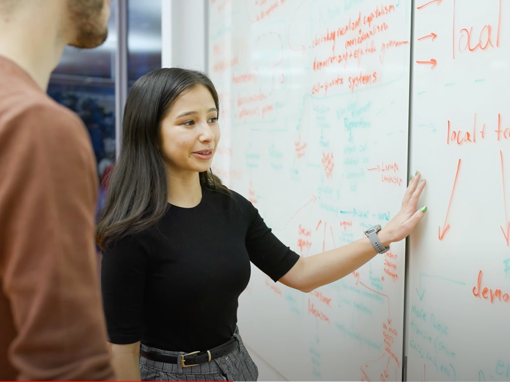 Two students looking at information on a white board