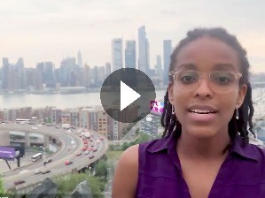 Young woman looking at camera with city skyscrapers behind her