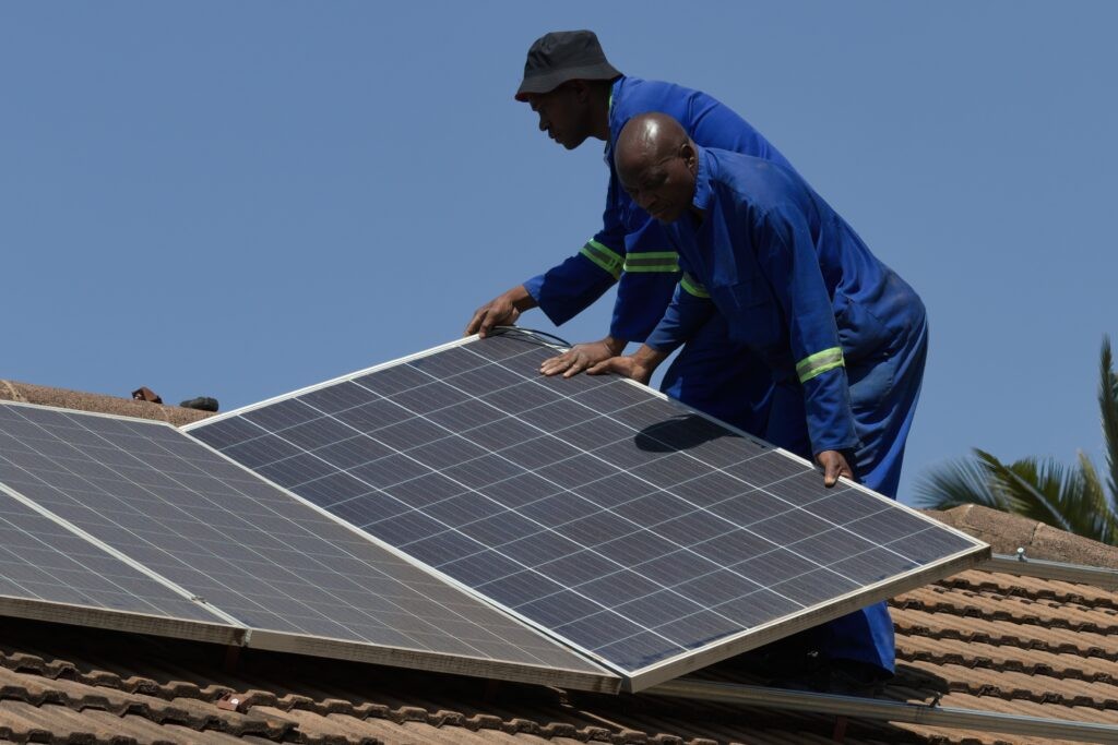 Harare Zimbabwe, August 26 2022, Two men installing solar panels on a house roof (via Shutterstock).