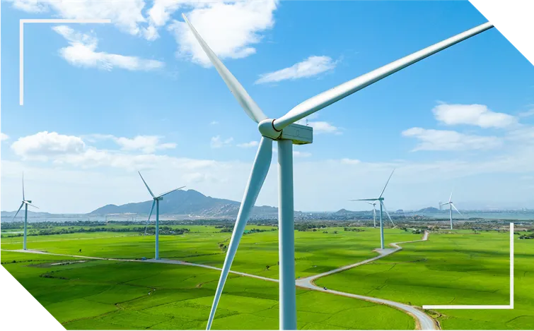 Wind turbines on a green landscape with blue skies and mountain in the background
