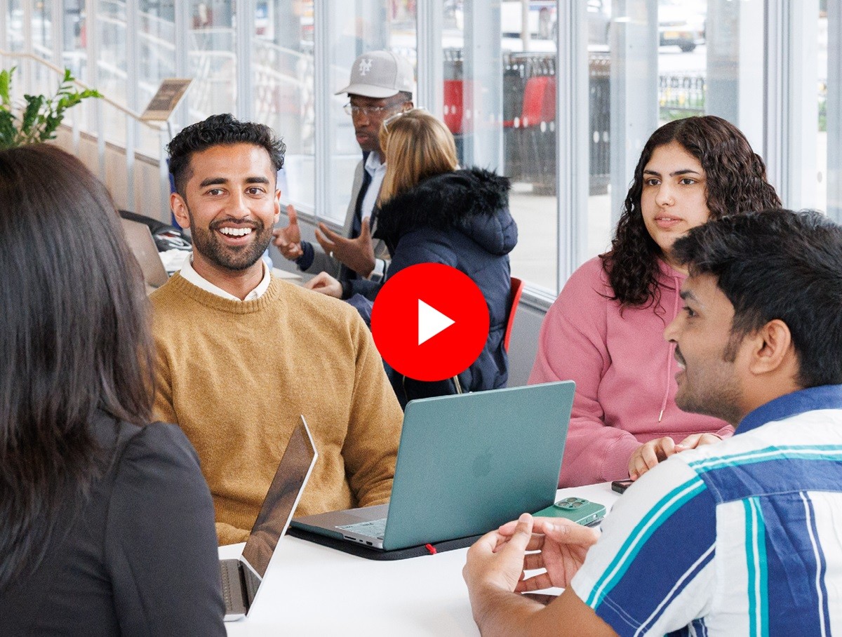 Four students sitting in a group with laptops on table