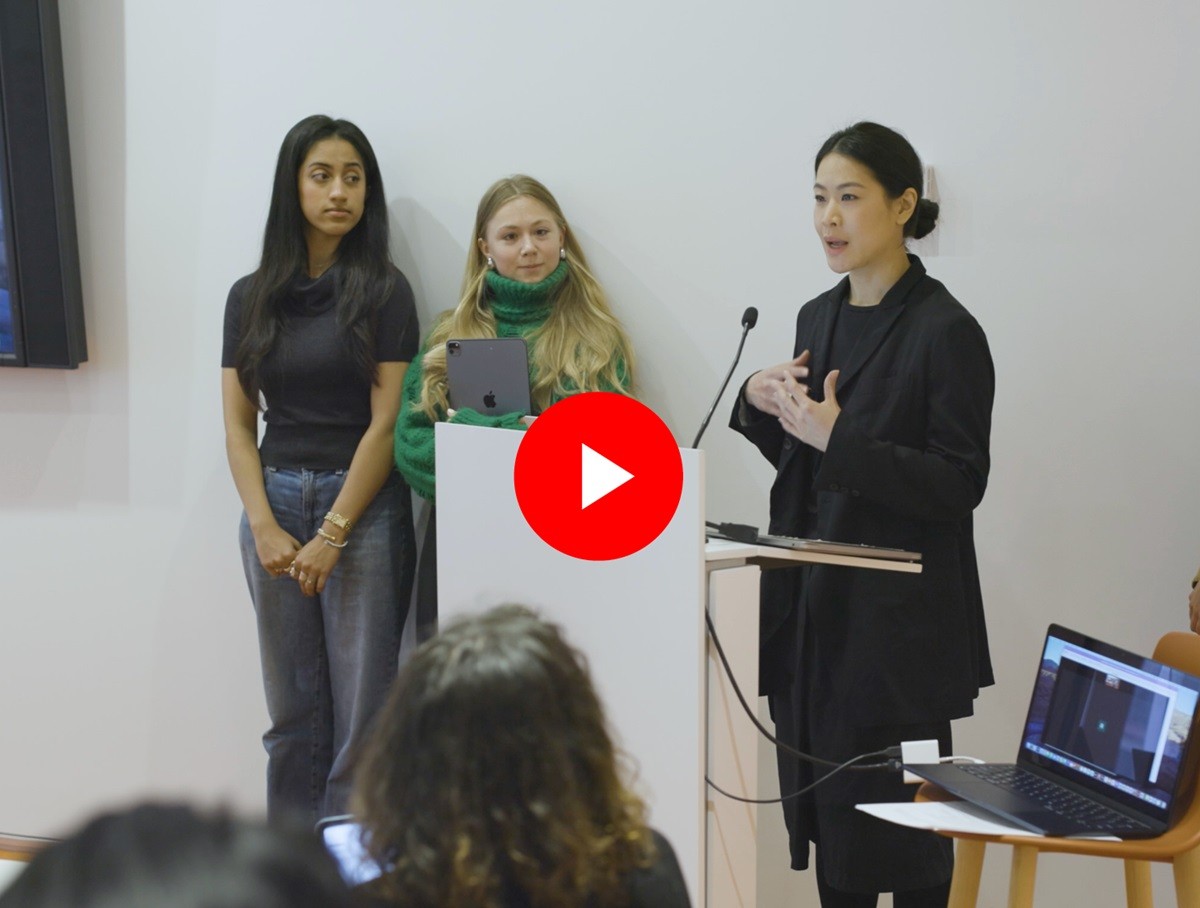 Three students standing at a podium presenting to a class