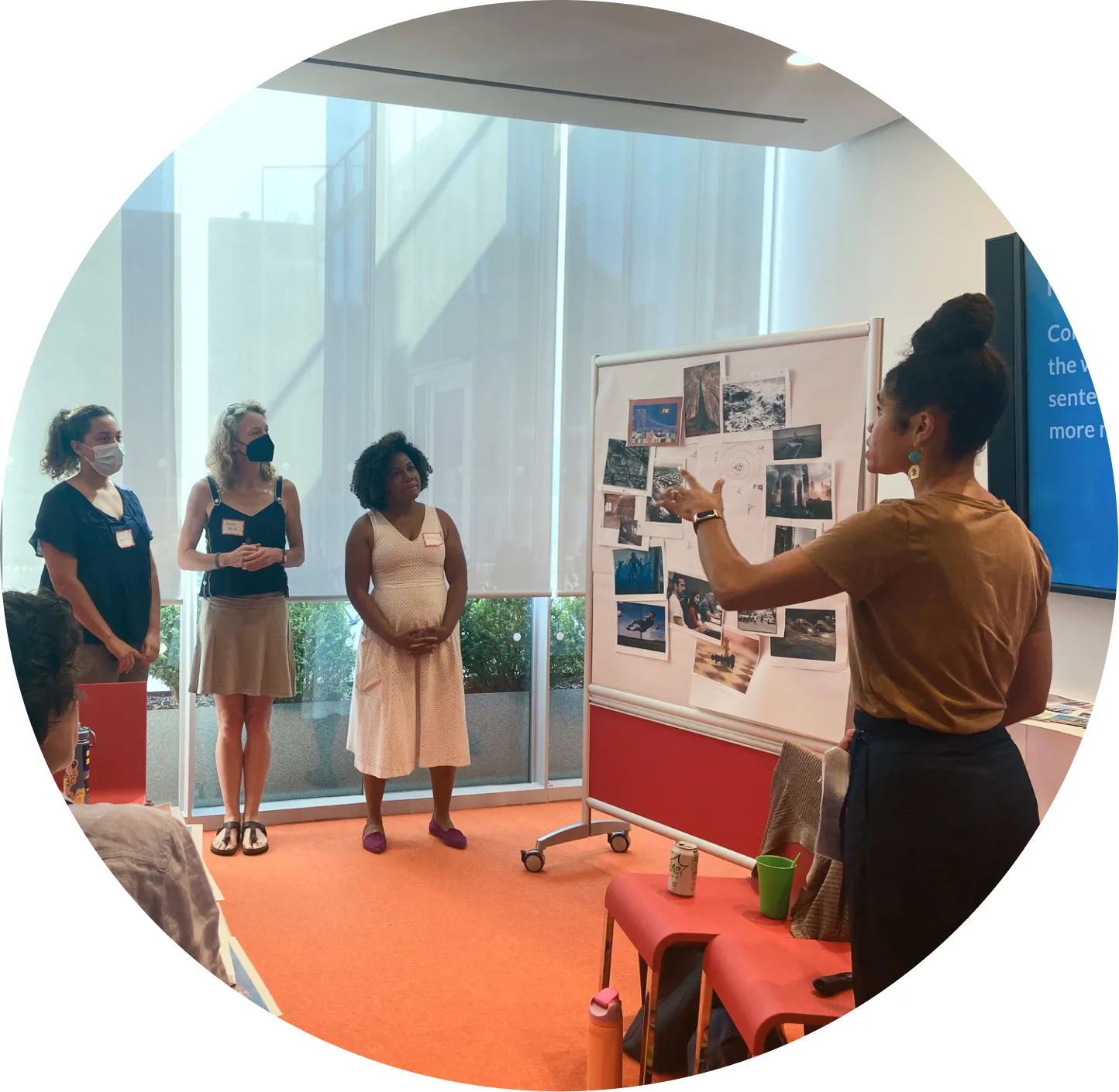 Group of people watching a presentation with a white board of photos.
