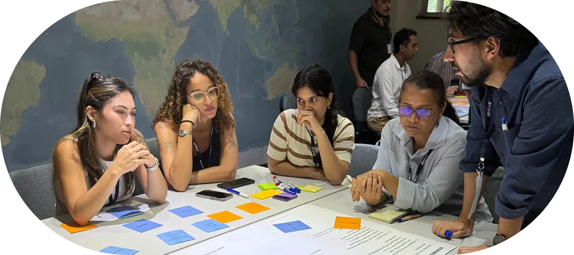 Group of five people collaborating at a table with posters and sticky notes