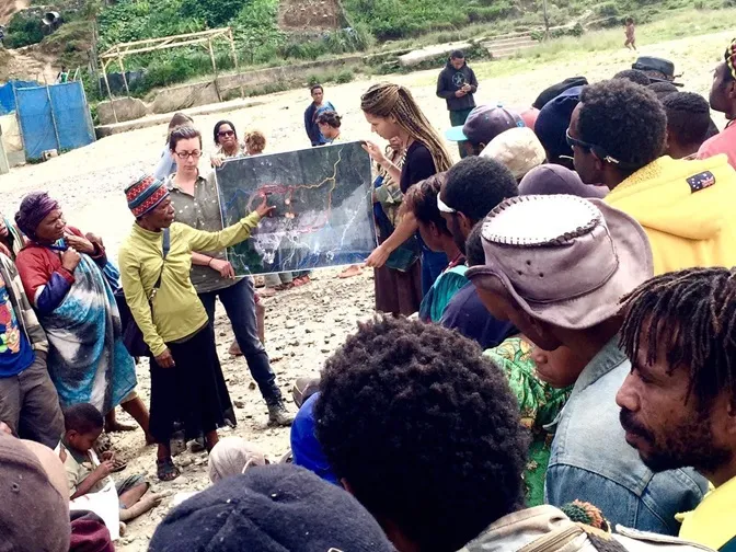 Large group of people gathered around presentation of map.