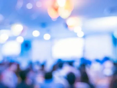 Blurry image of a brightly lit room full of people