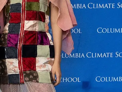 Woman in a patchwork jacket in front of Columbia Climate School step-and-repeat