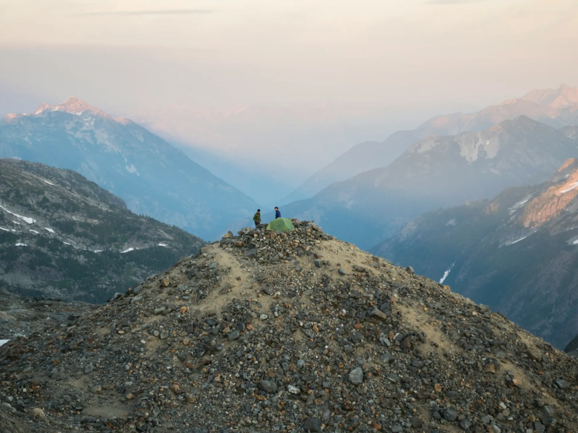 Two people on top of a mountain surrounded by other mountains