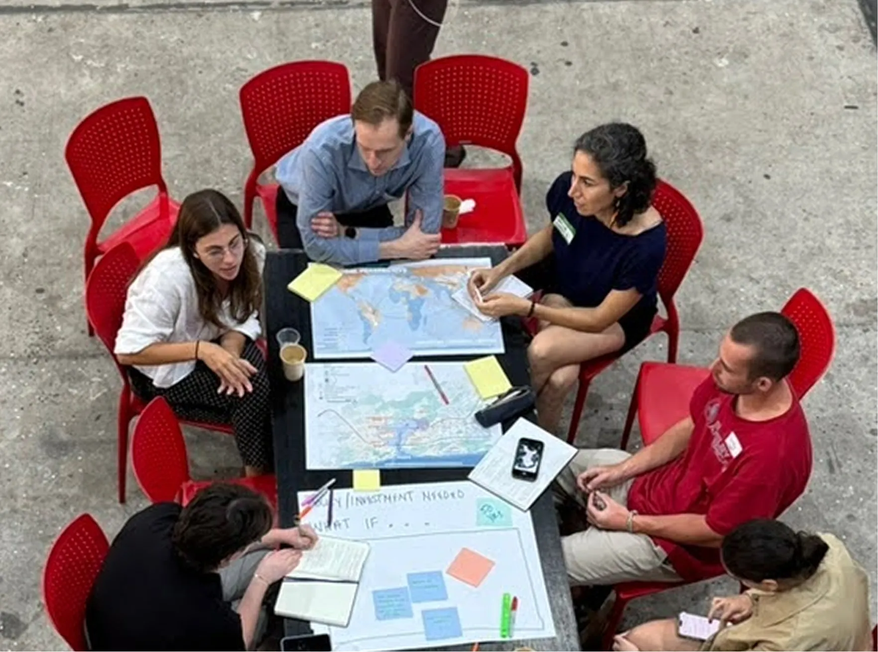 Five people around a table working on maps and posters.