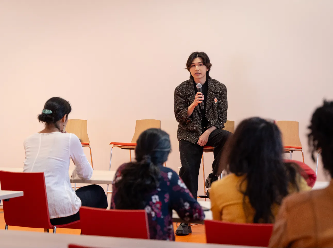 Person speaking on a microphone to a group of seated people