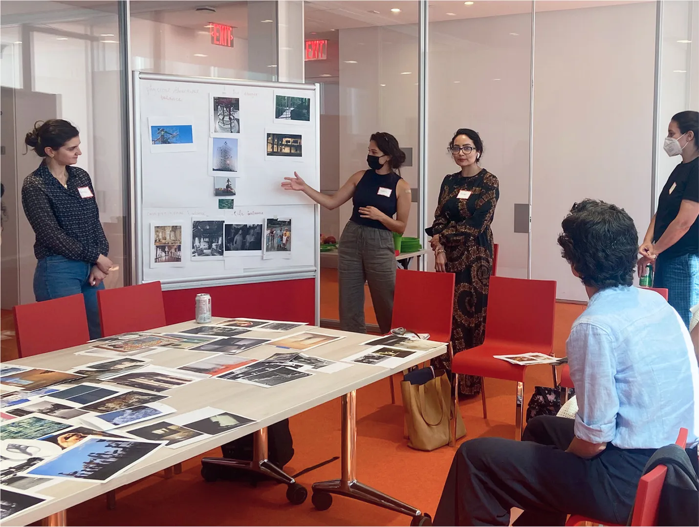 Group of people watching a presentation with a white board of photos.
