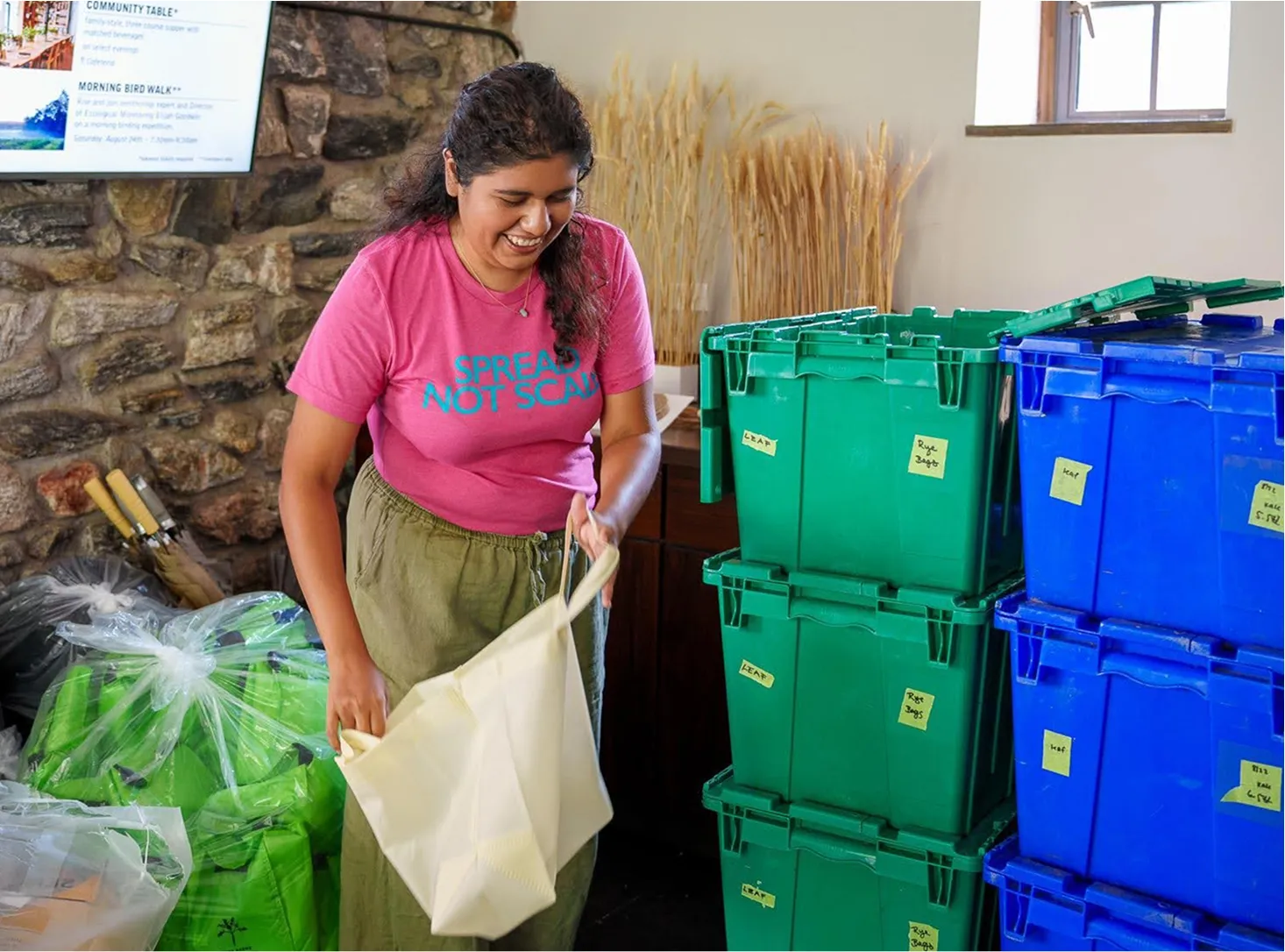 Smiling woman holding an open tote bag with stacks of colorful crates