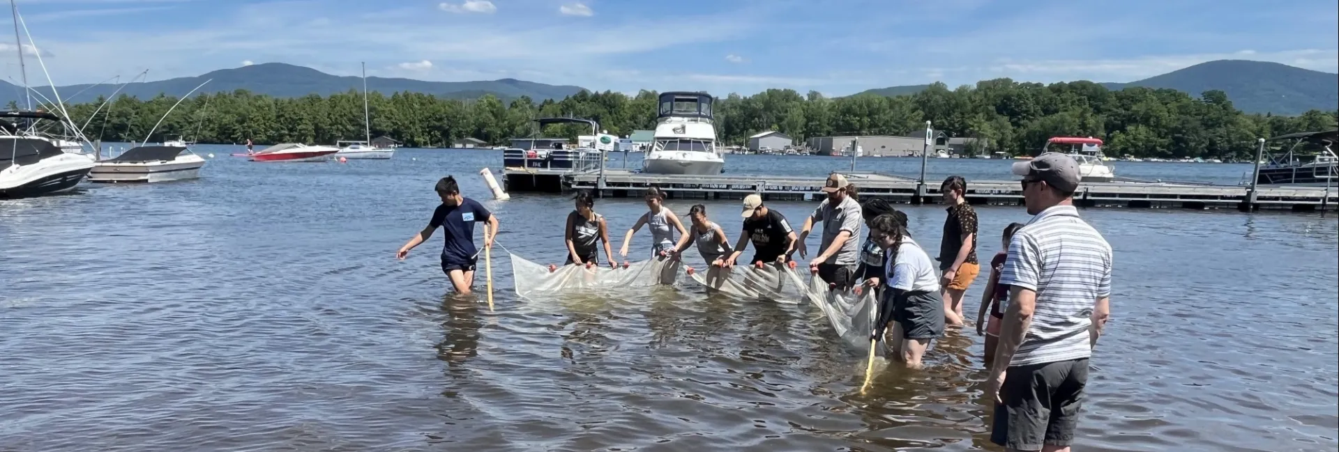 Students moving through lake holding a large net