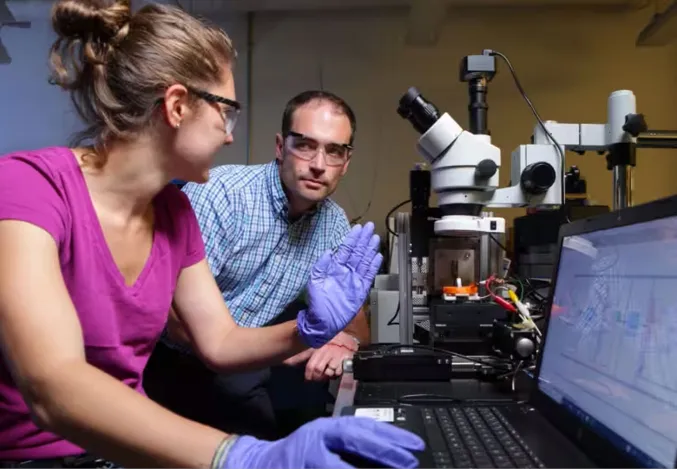 Two people in a lab with a laptop and equipment