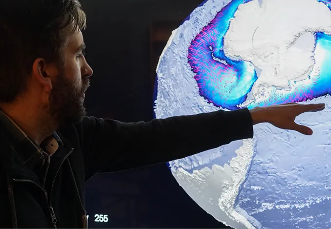 Person pointing to a glowing satellite map on a screen