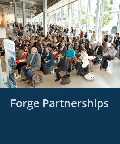 Large group of people watching a presentation with the text Forge Partnerships